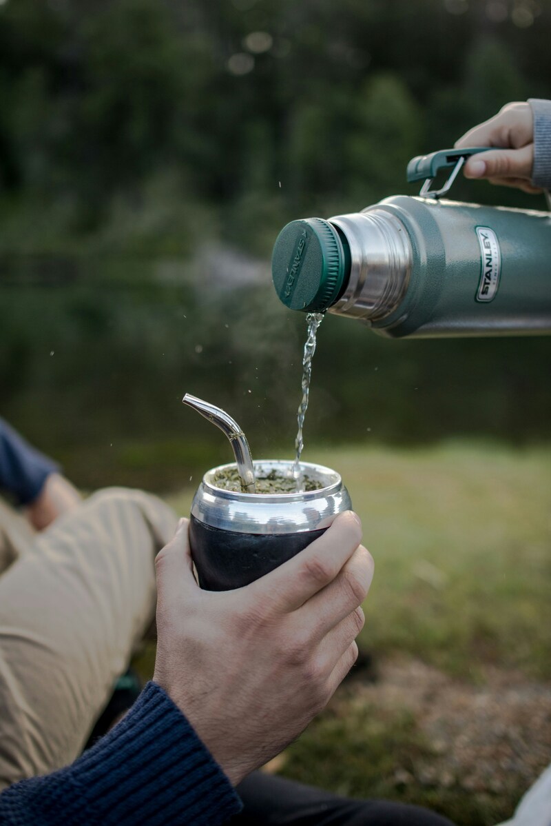 Stainless steel mate cup with bombilla on an outdoor table, gifts for yerba mate lovers